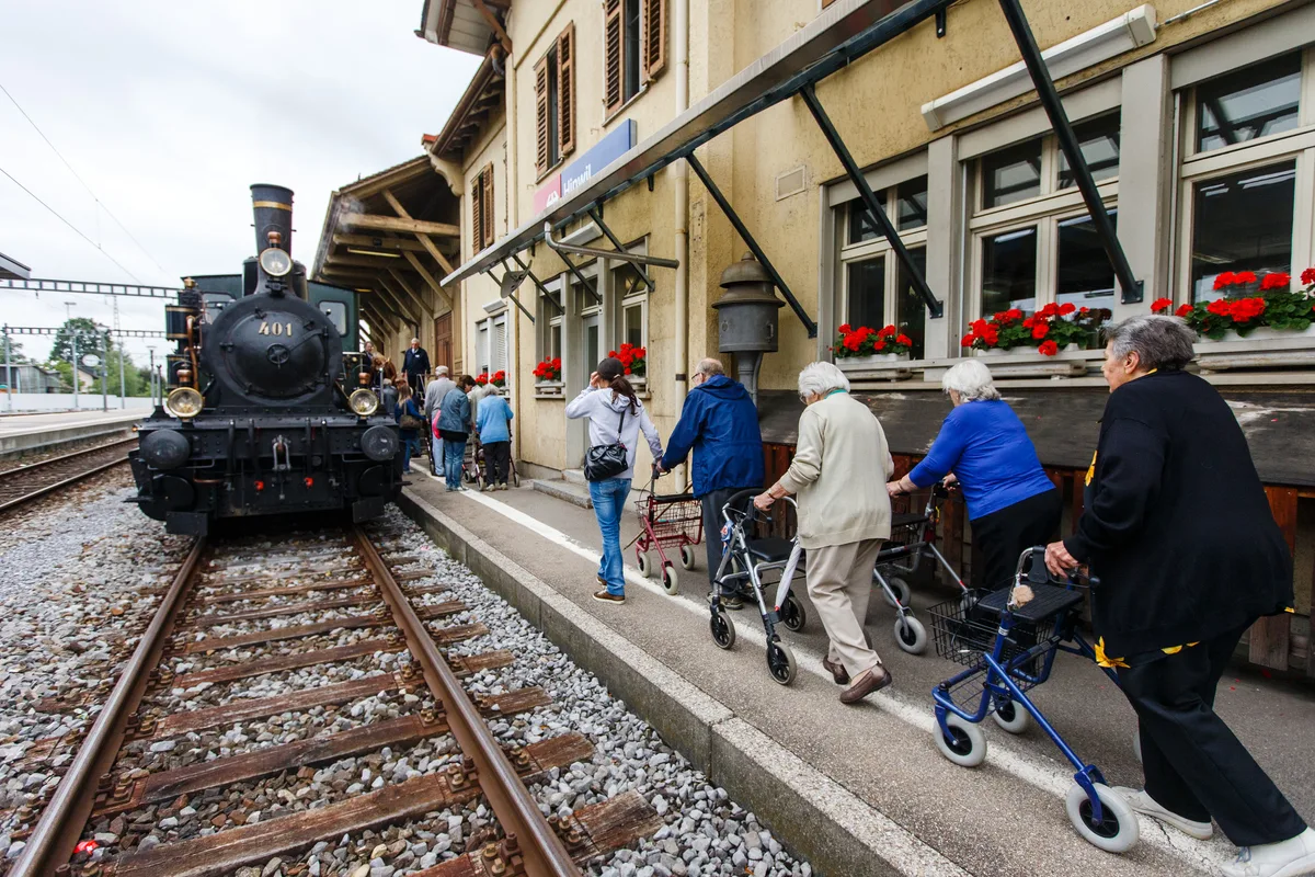 Mehrere Leute mit Rollatoren sind unterwegs beim Bahnhof Hinwil.